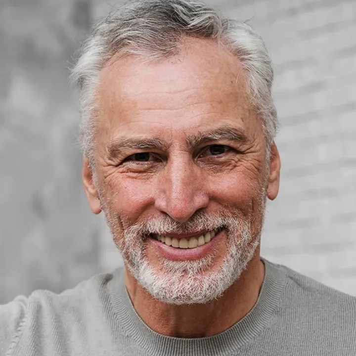 A smiling older man with gray hair and a beard