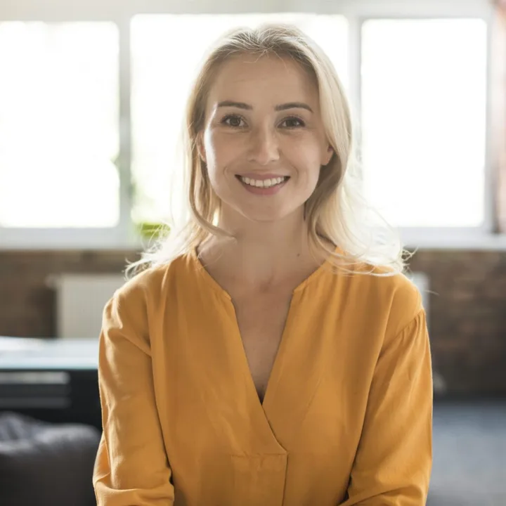 A smiling woman with blonde hair in a yellow blouse